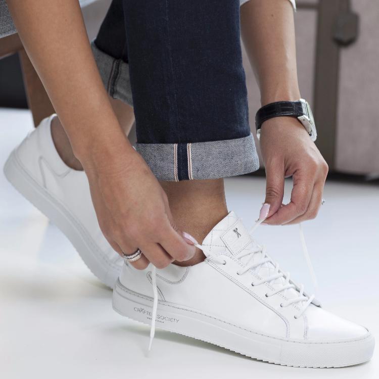 Woman putting on white sneaker