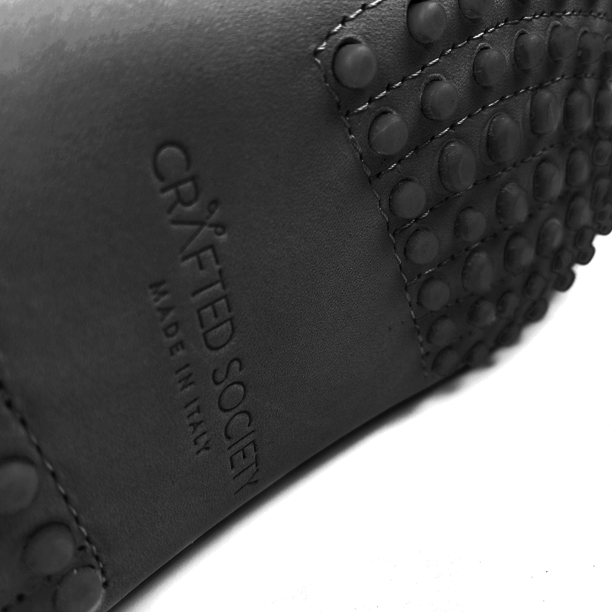Driving shoe or moccasin in black italian nubuck. close-up detail of bottom of shoe with iconic rubber pebble outsole and crafted society logo made in italy embossed in the leather